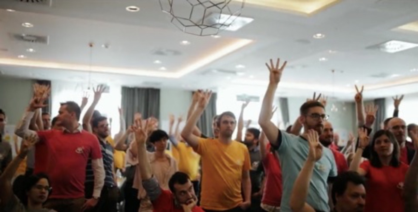 A large group of workshop participants raising their hands